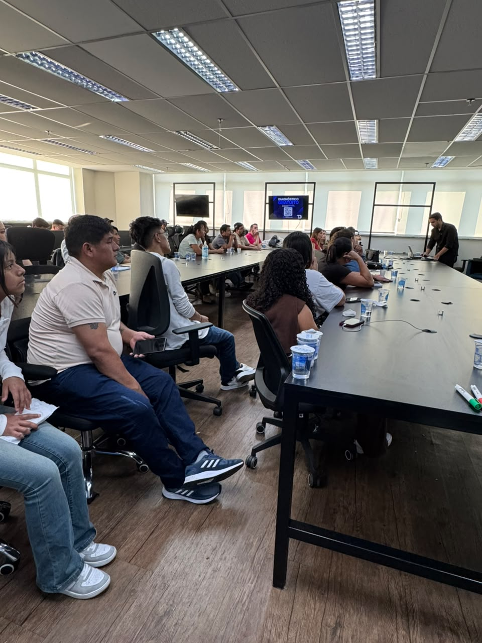 Participantes acompanhando a apresentação na sala do Grupo TG
